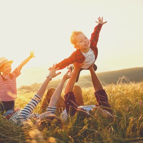 family playing in field playing plane ride with mom and dad