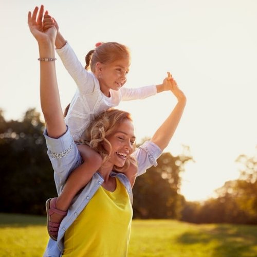 mom with little girl on shoulders little girl happy on mom shoulders
