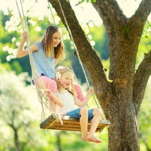 sisters swinging and smiling teeth at ages 5 and 10